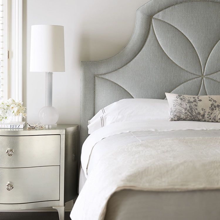 Glamorous bedroom with upholstered headboard with nail head design and metal finish chest for side table.