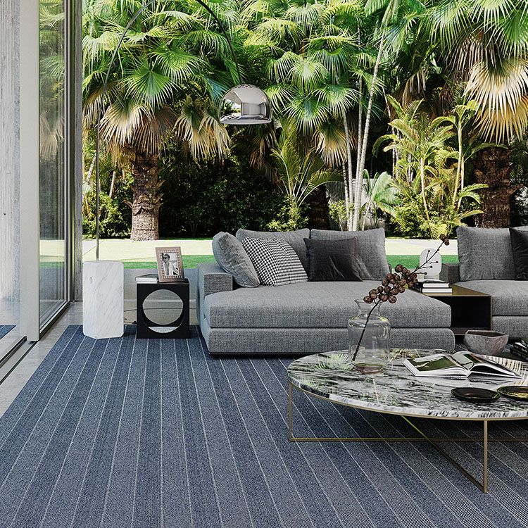 Modern casual outdoor living room with upholstered furniture on a striped rug.