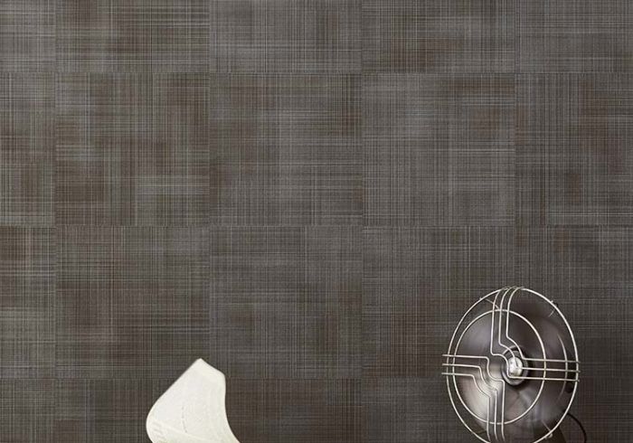 Woven wall covering with vintage fan in foreground.