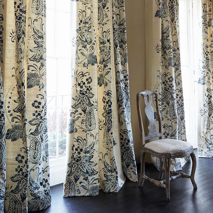 Traditional dining chair in front of windows with floor to ceiling drapes in a floral pattern.